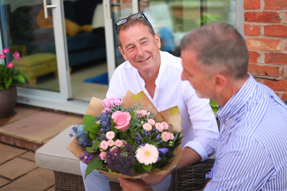 Two men in garden admiring bouquet of flowers delivered same day by local florist
